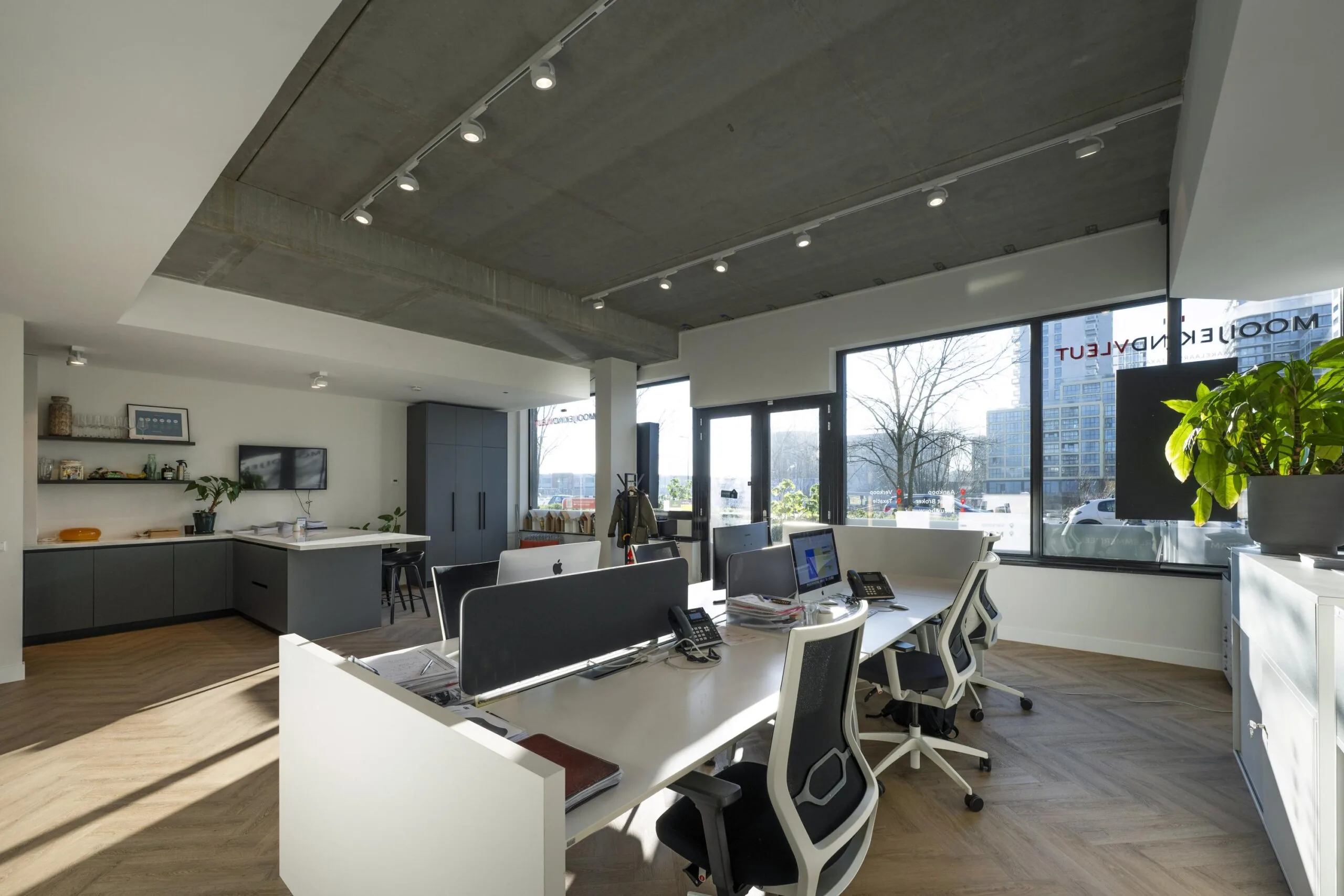 Een modern kantoorinterieur met bureaus, stoelen en veel natuurlijke lichtinval.