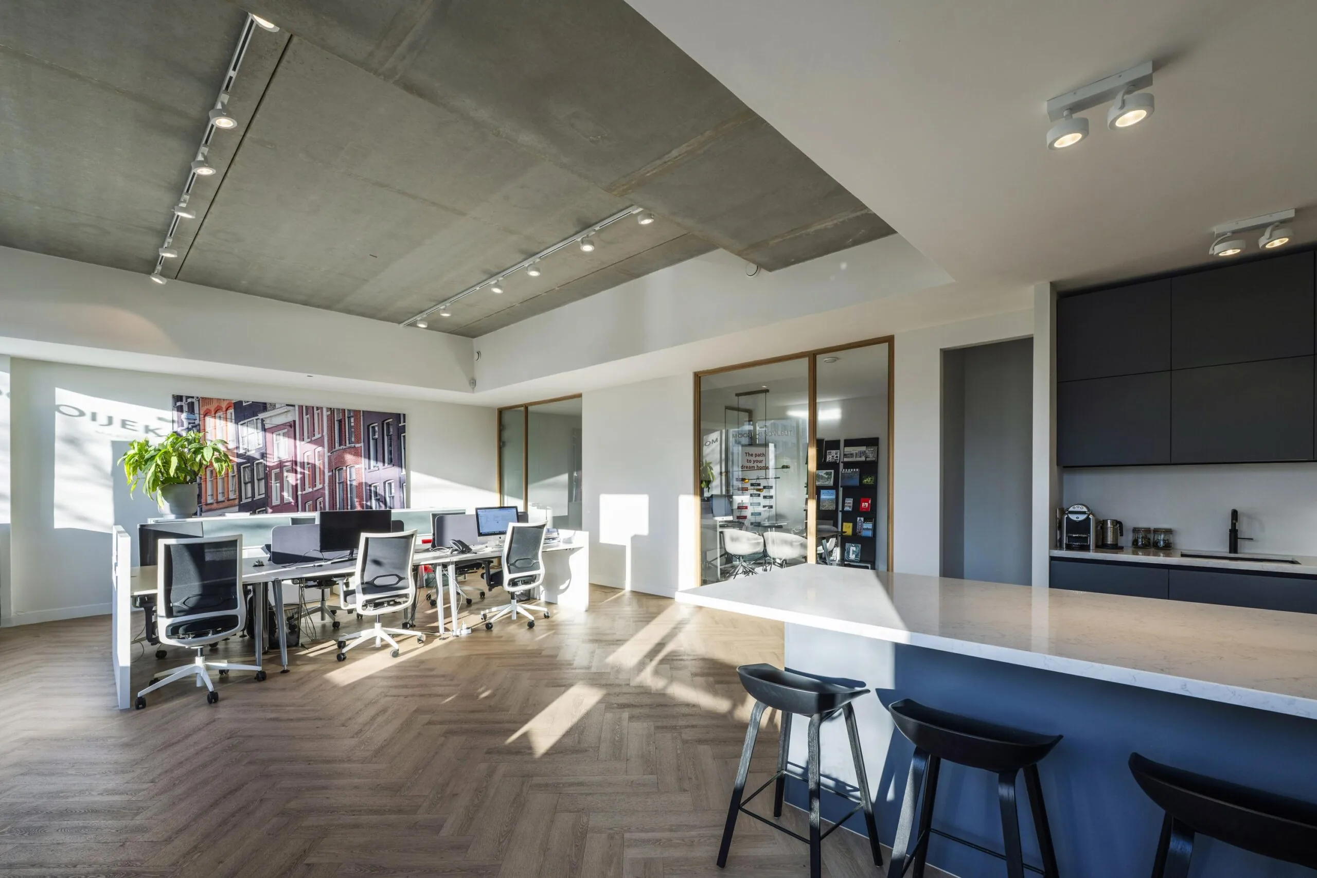 Een moderne, goed verlichte kantoorruimte met bureaus, stoelen en een keukenhoek.