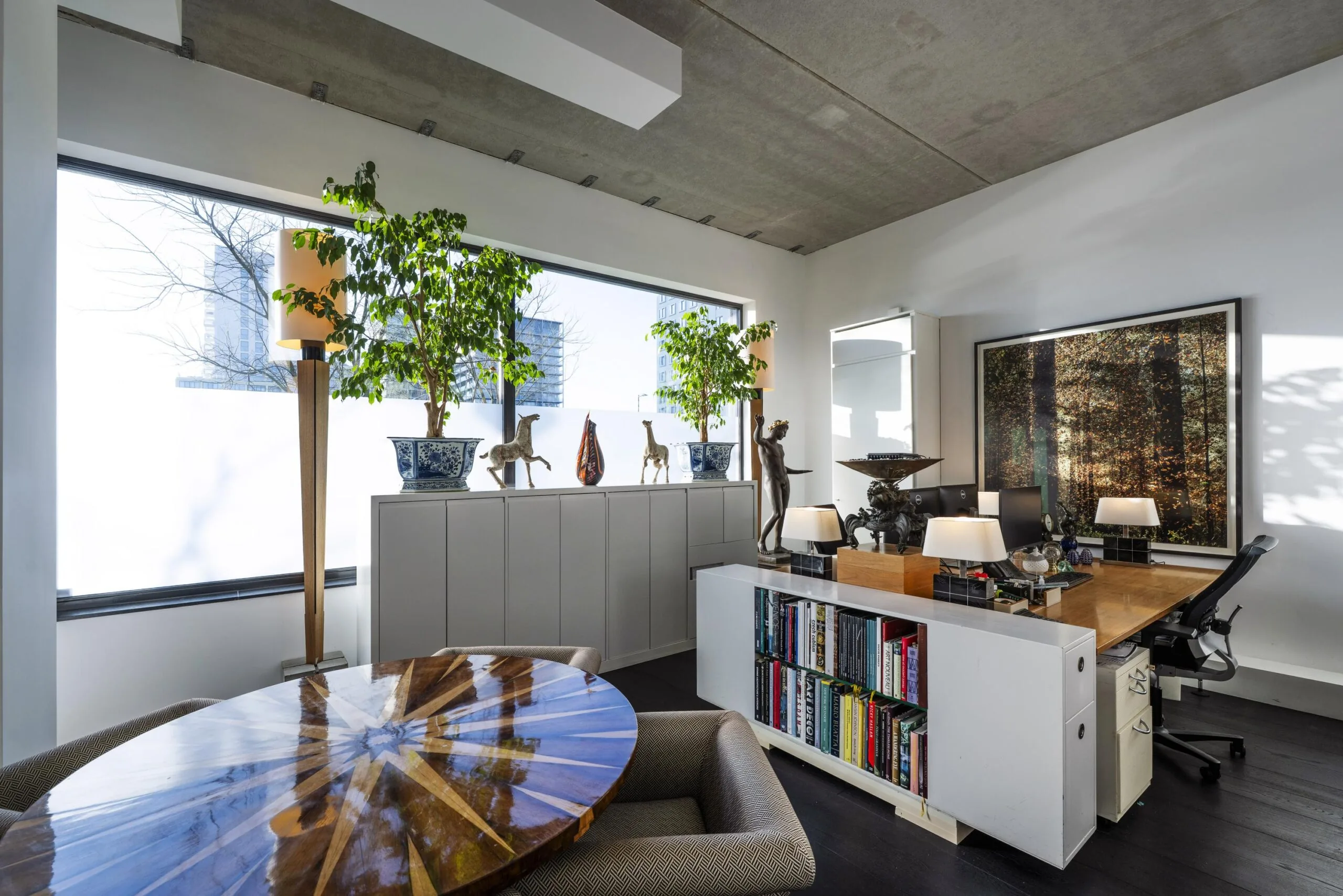 Een moderne kantoorruimte met planten, kunstobjecten en een boekenplank.