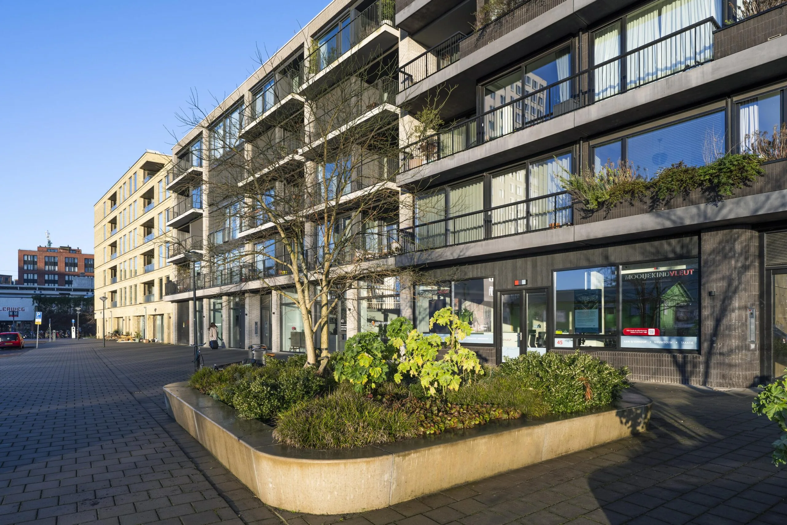 Moderne appartementencomplexen aan de Lindenhoevestraat met een plantenbak en een betegeld plein op de voorgrond.