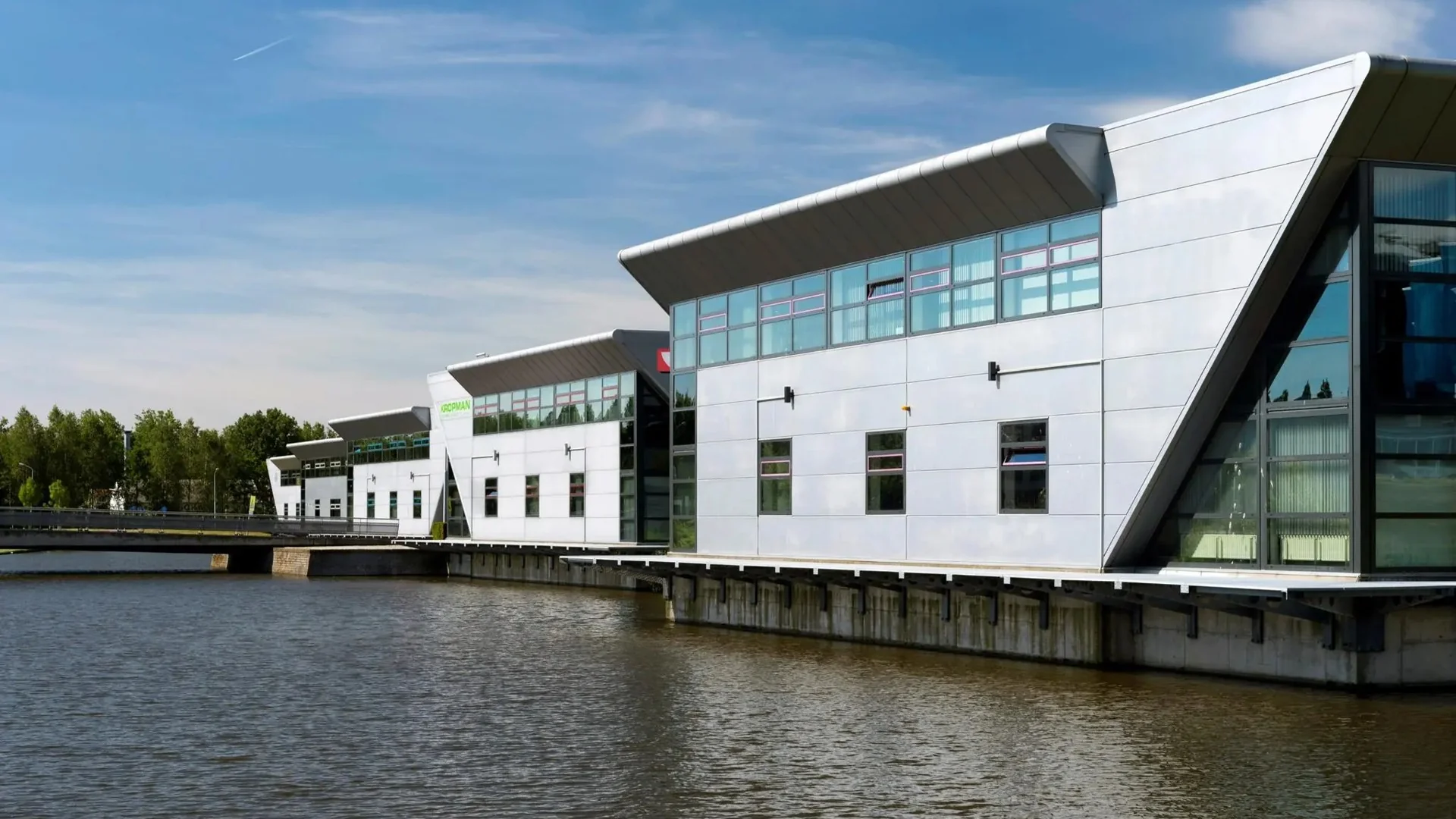 Moderne kantoorgebouwen langs een waterkant in een stedelijke omgeving.