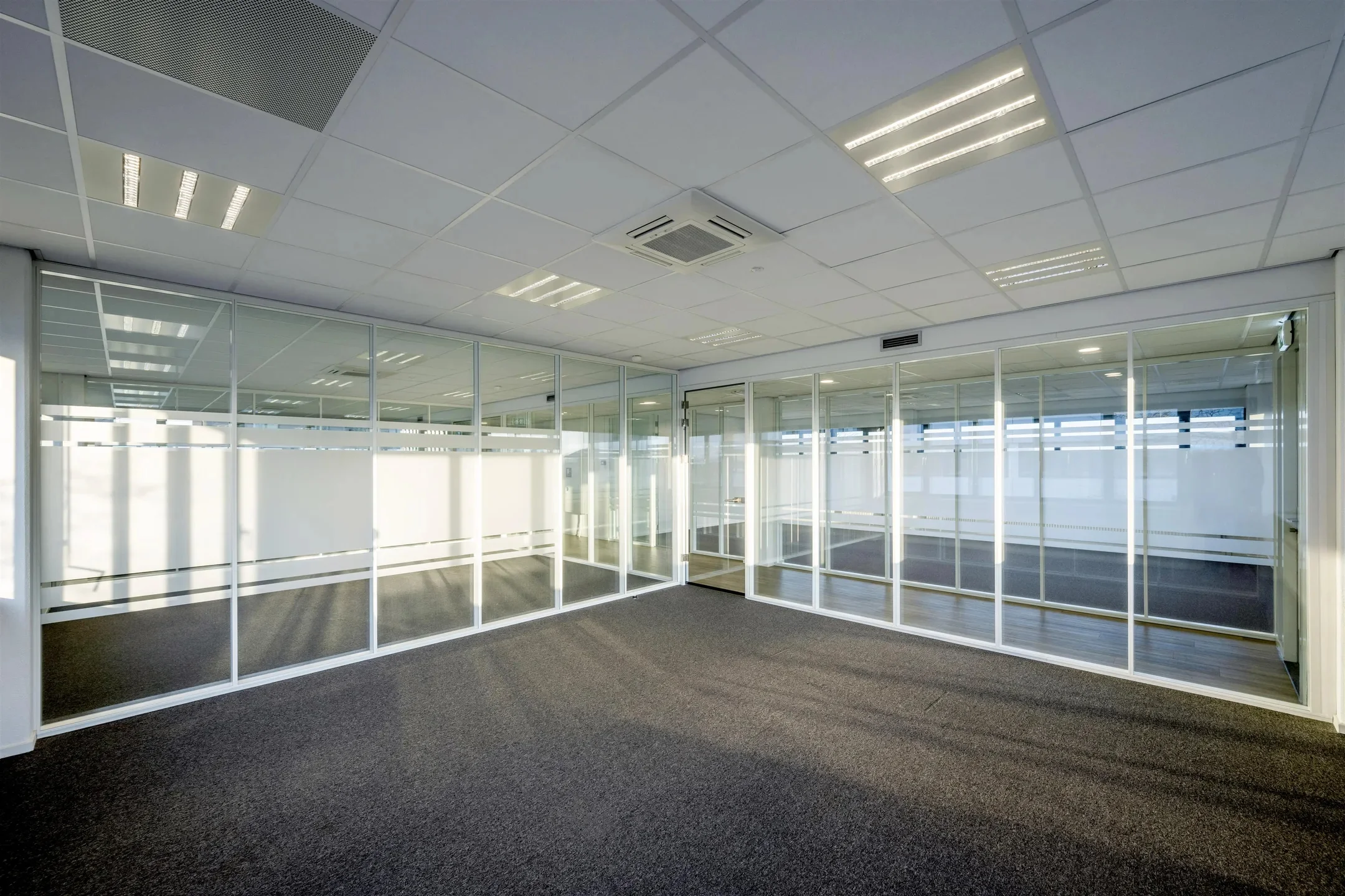 Leeg kantoorinterieur met glazen wanden en systeemplafond bij Atoomweg.