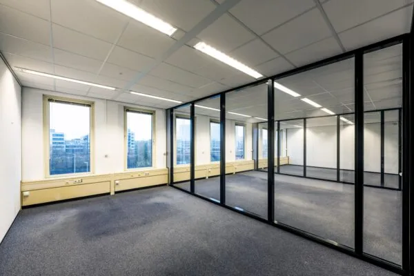 Een leeg kantoor op Neptunusstraat met glazen wanden en uitzicht op omliggende gebouwen.