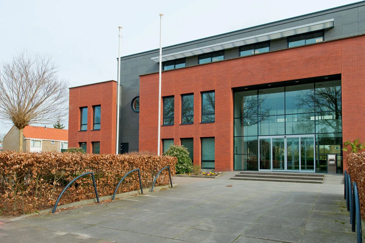 Een modern gebouw met rode bakstenen en grote glazen entree aan de Groenekanseweg.