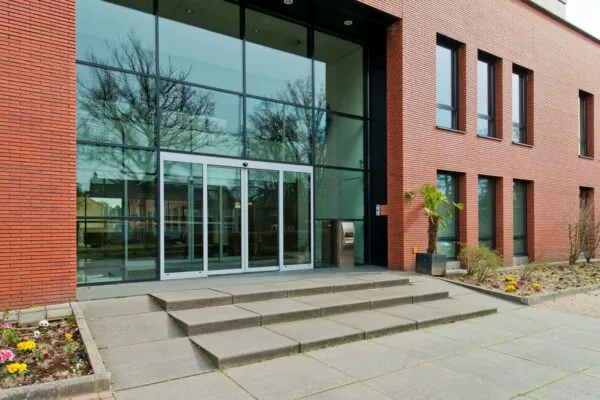 Ingang van een gebouw aan de Groenekanseweg met grote glazen deuren en een rode bakstenen gevel.