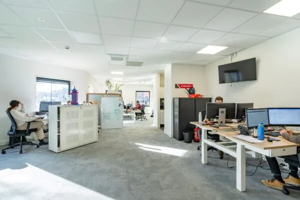 Een modern en licht kantoor met meerdere werkplekken waar mensen geconcentreerd aan het werk zijn.