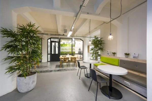 Moderne, open kantoorlounge in HNK Diemen met zitplekken, veel groen en glazen vergaderruimte op de achtergrond.