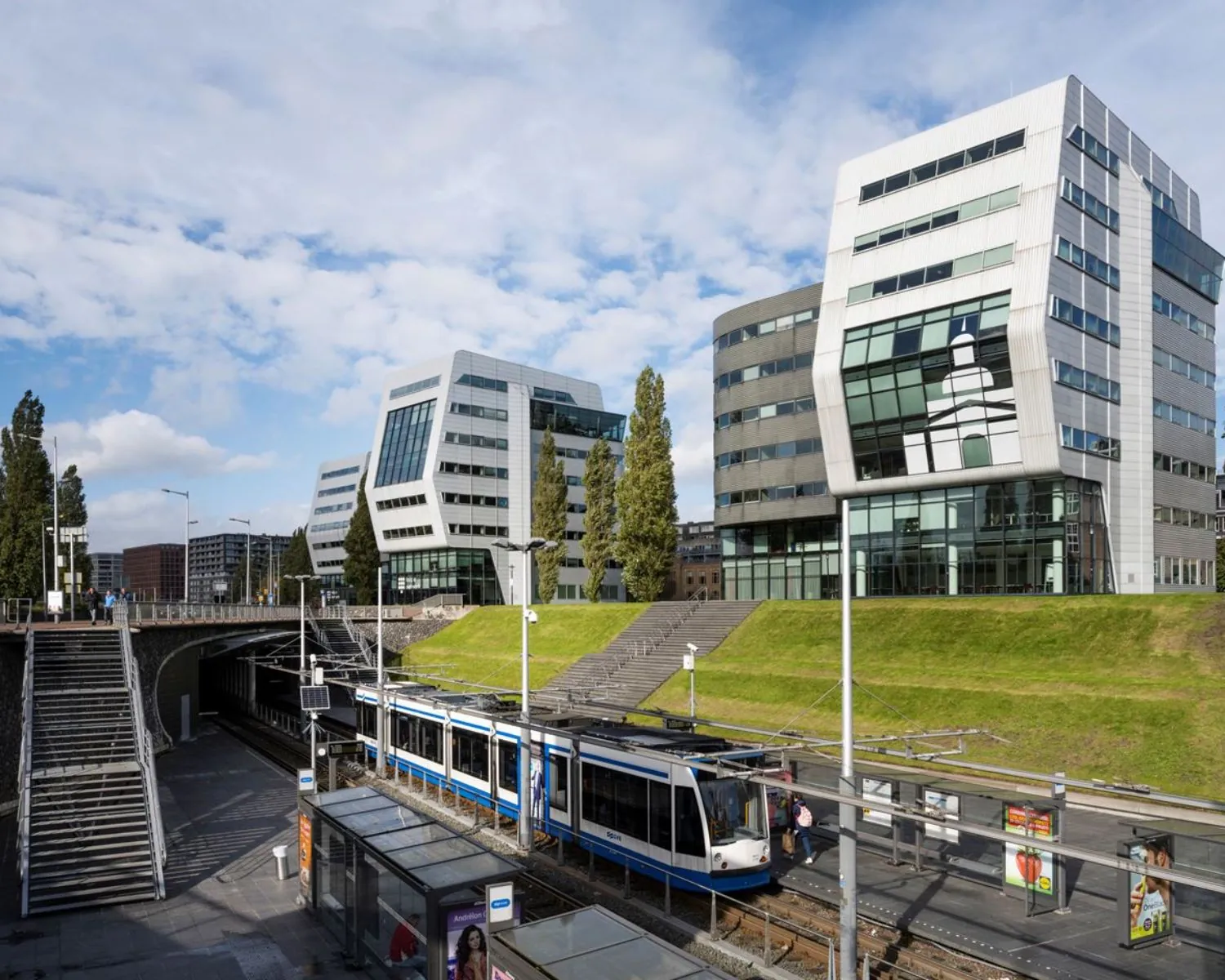 Modern kantoorgebouw aan het Rietlandpark in Amsterdam met een tramhalte op de voorgrond.