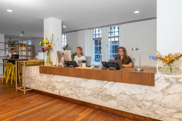 Receptiebalie met medewerkers en een stijlvolle marmeren afwerking in een modern kantoorinterieur.