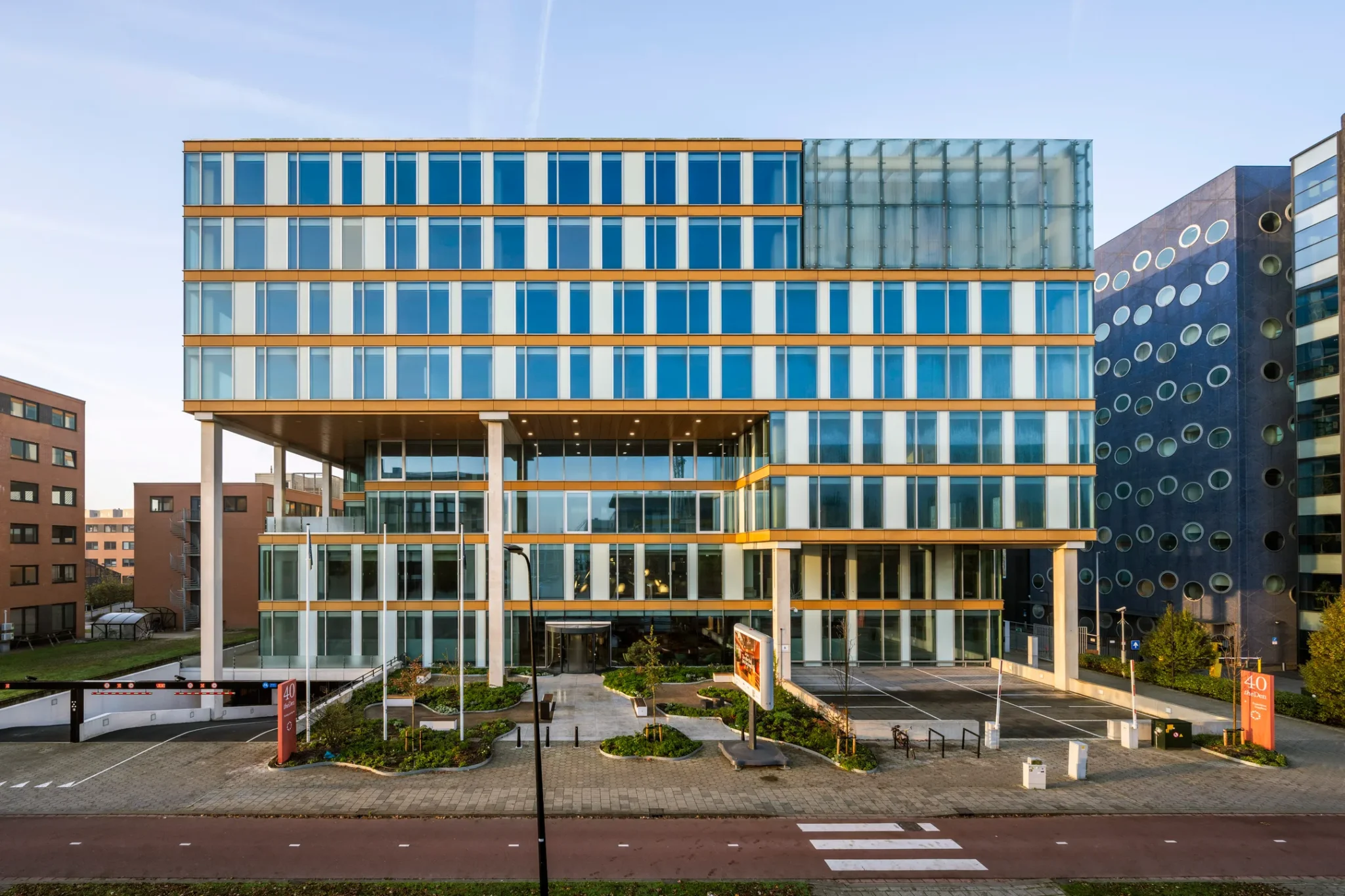 Modern kantoorgebouw met glazen gevel en gele accenten, gefotografeerd vanaf de straatkant.