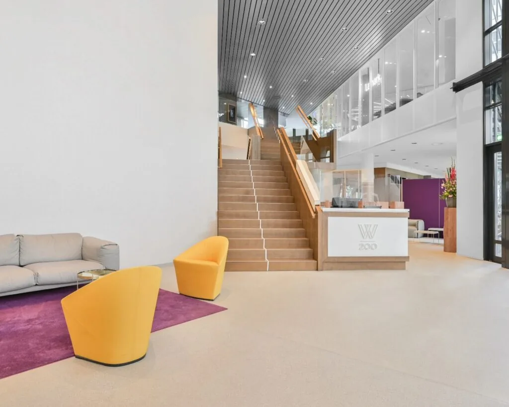 Moderne lobby van kantoorpand Weena 209 in Rotterdam met zitgedeelte, receptiebalie en houten trap.
