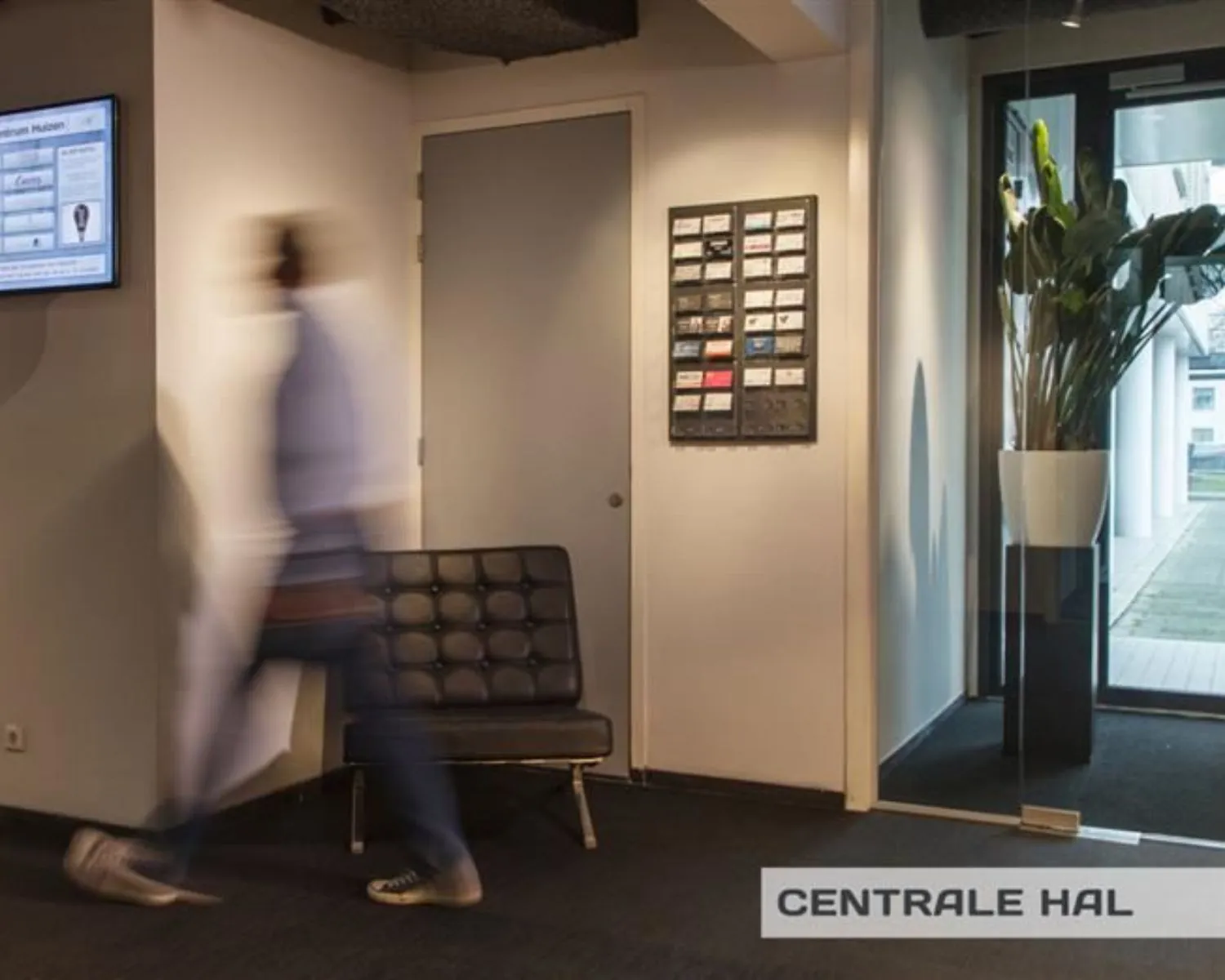 Moderne hotellobby van The Den met een chique receptiebalie, designmeubels en veel groen.