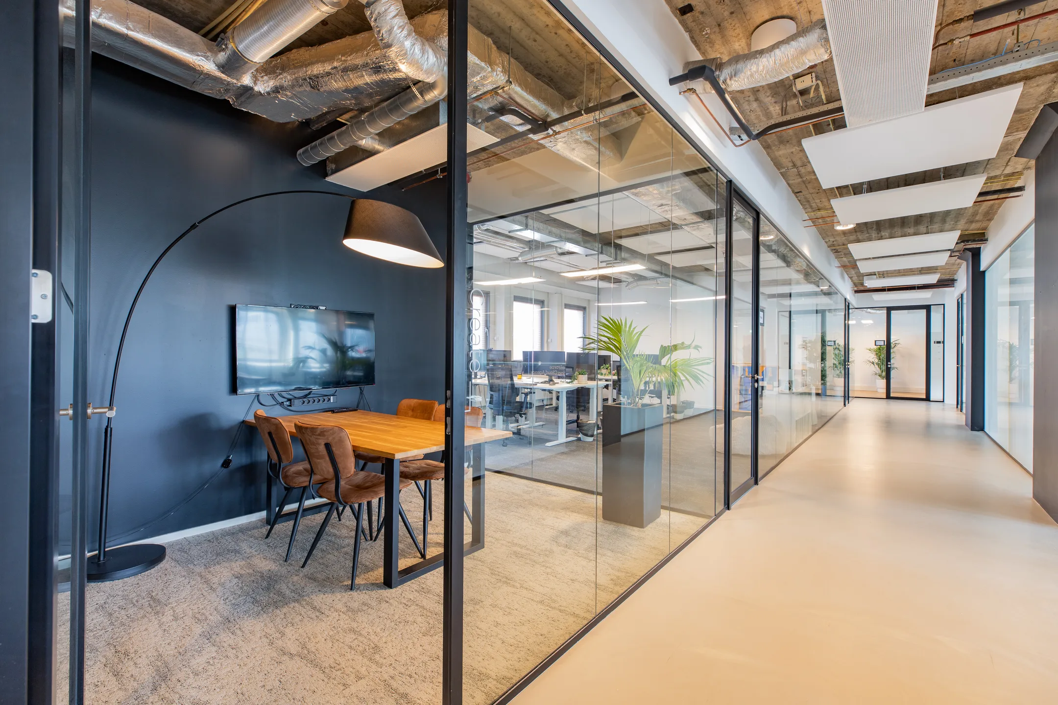Moderne kantoorruimte met glazen wanden, een vergadertafel en open werkplekken.