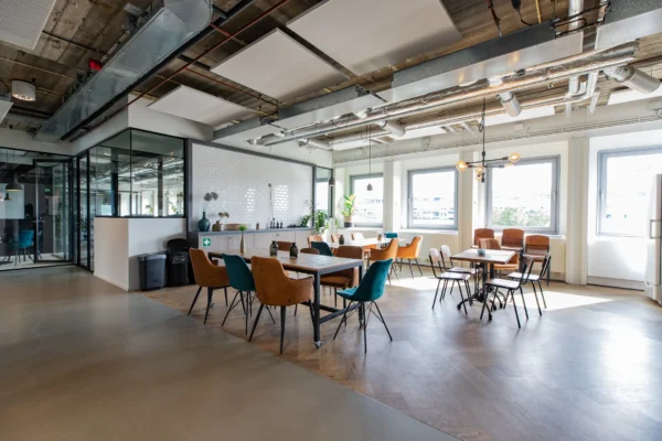 Een moderne, lichte kantoorruimte met diverse tafels en stoelen.
