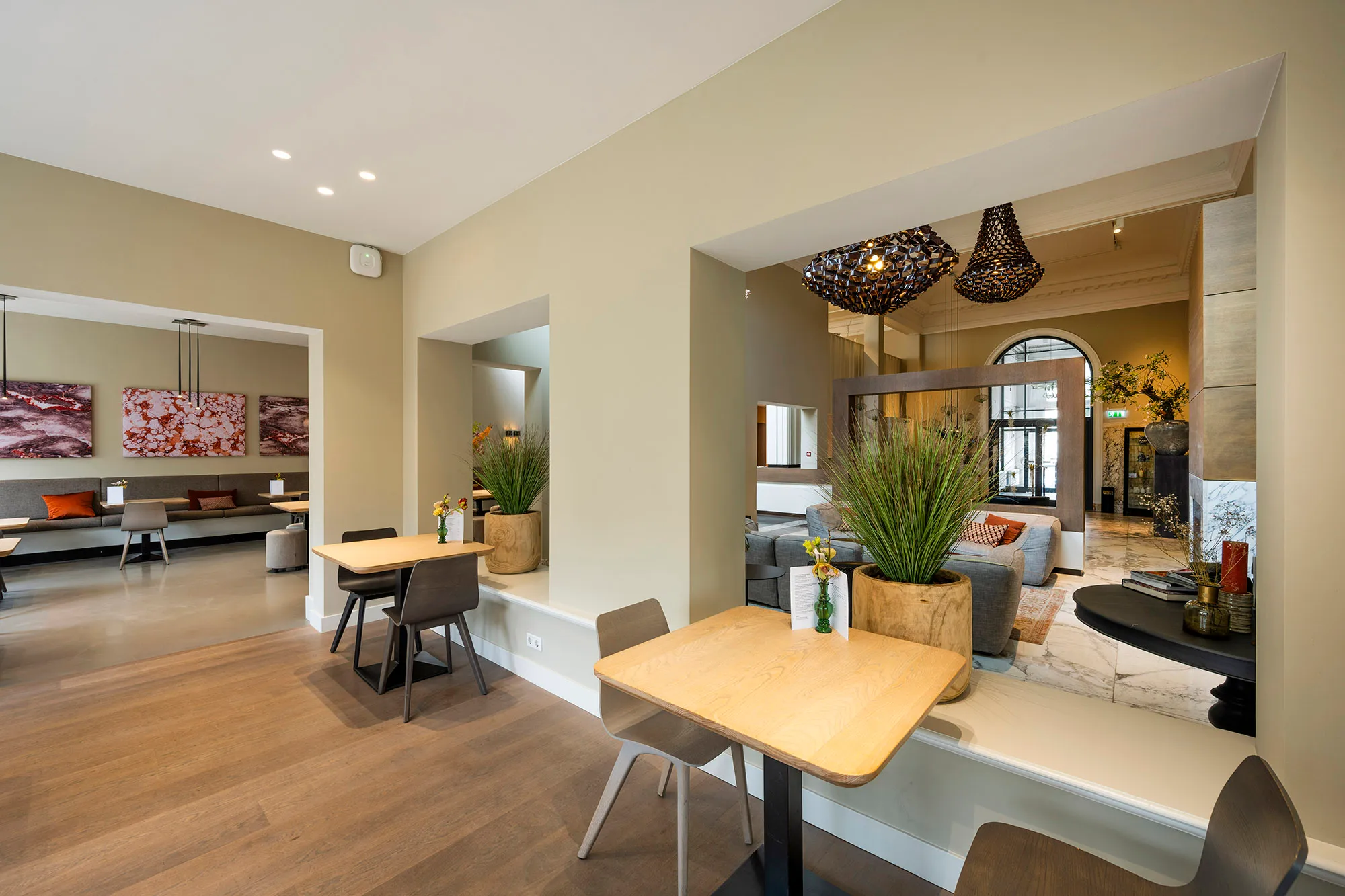 Een modern ingerichte ruimte met zithoeken, houten tafels en decoratieve planten.