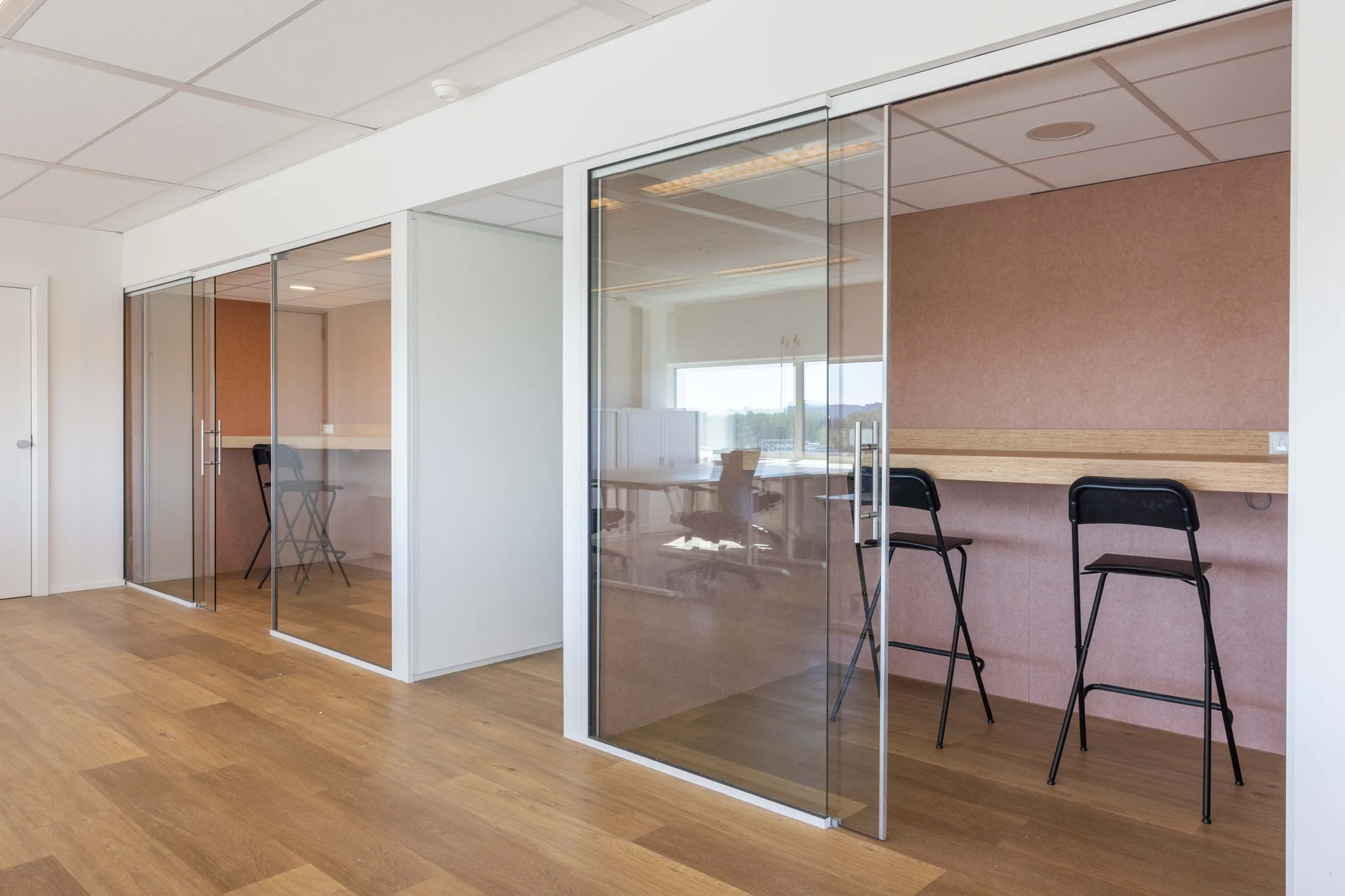 Een moderne kantoorruimte met glazen wanden en houten tafels.