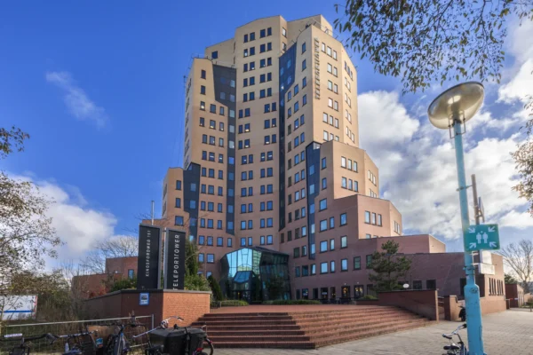 Een groot, modern gebouw genaamd Kingsfordweg 151, ook bekend als Teleport Tower, onder een heldere blauwe lucht.