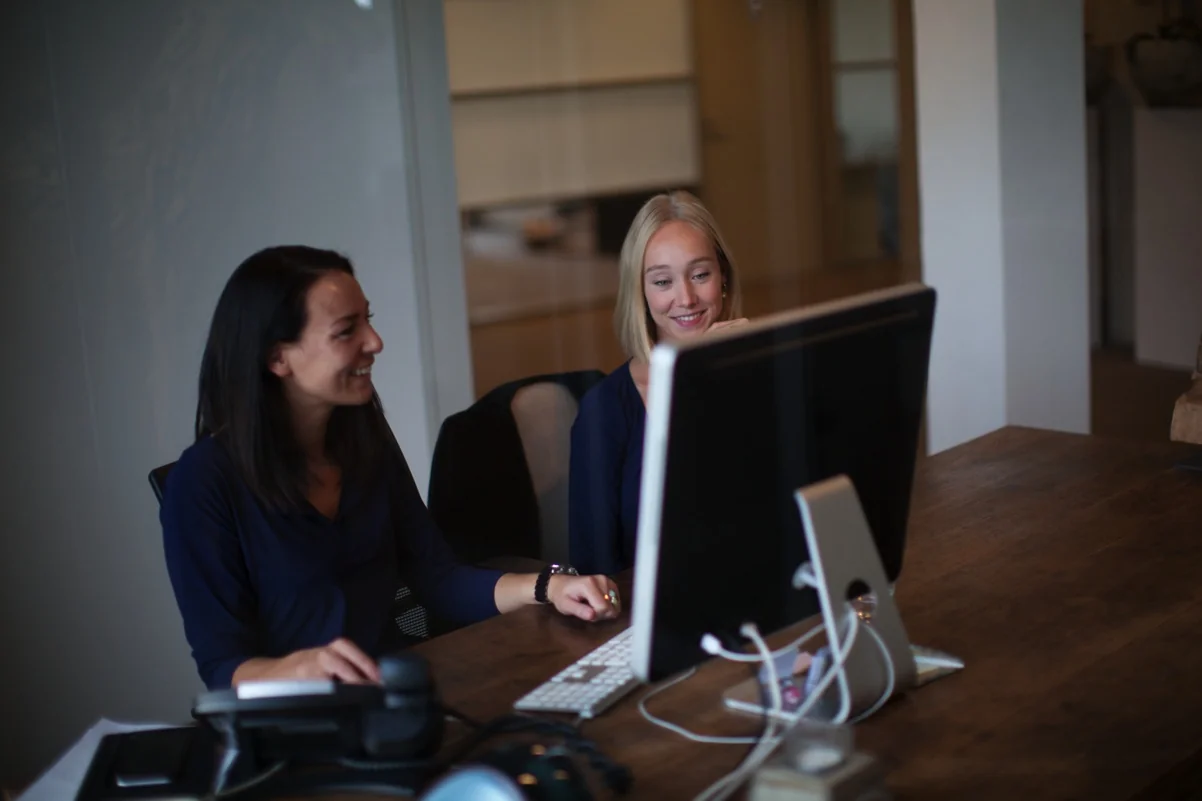Twee vrouwen werken samen achter een computer op een kantoor aan de Orteliuslaan.