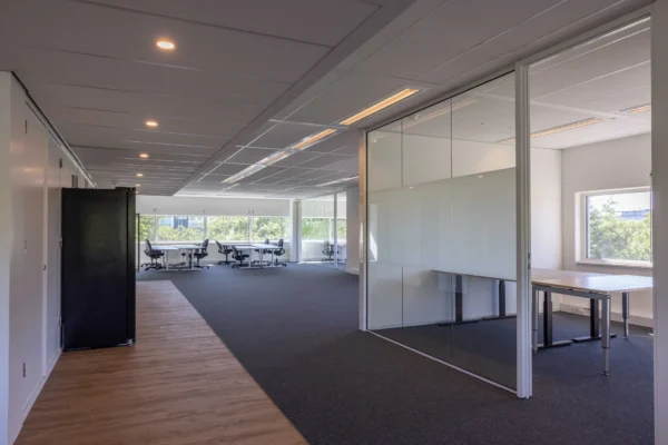 Een moderne, lichte kantoorruimte met glazen scheidingswanden en werkplekken.