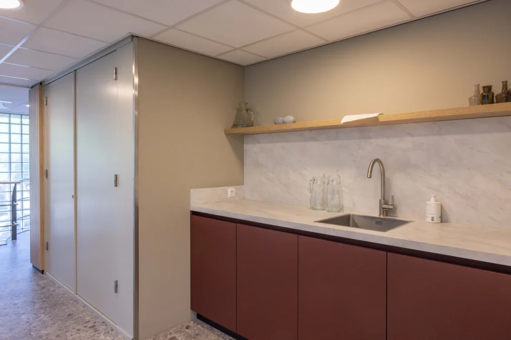 Een moderne keukenhoek met een marmeren aanrecht, gootsteen en houten plank met decoratieve elementen.