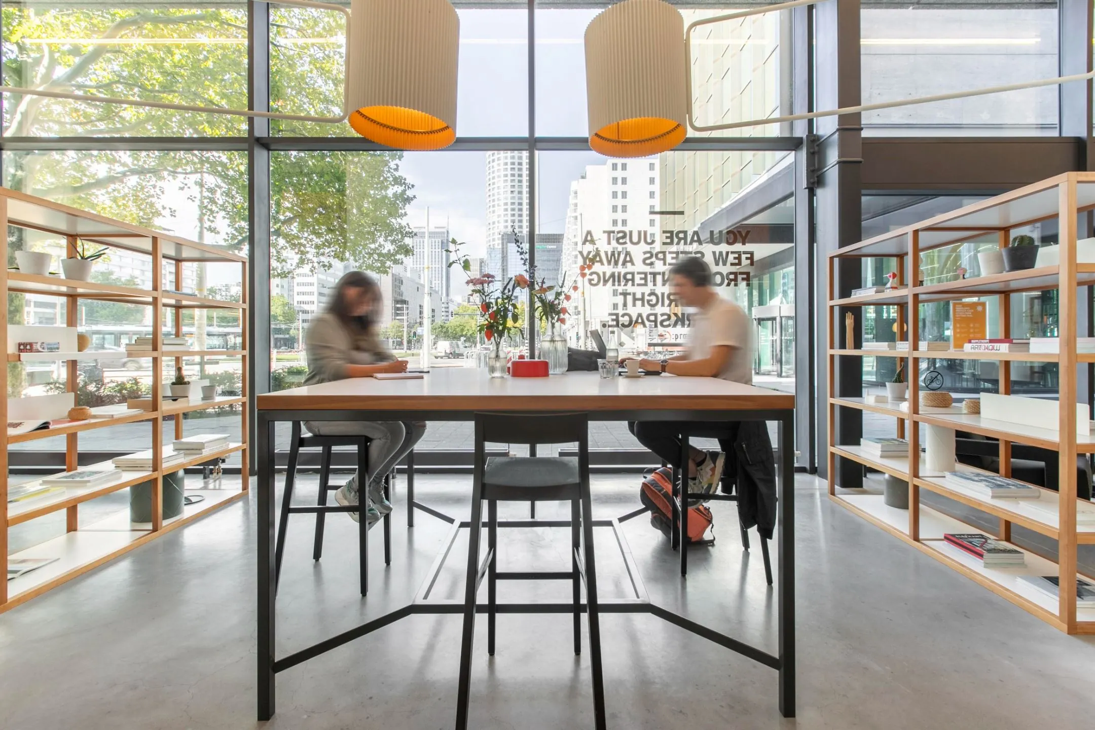 Moderne vergaderruimte met een houten tafel, vier beige stoelen en glazen karaffen.