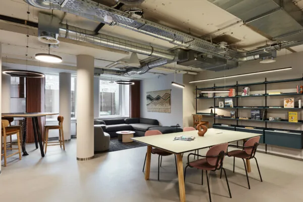 Moderne kantoorruimte aan de Koninginnegracht 10 in Den Haag met werktafels, een zithoek en open boekenkasten.
