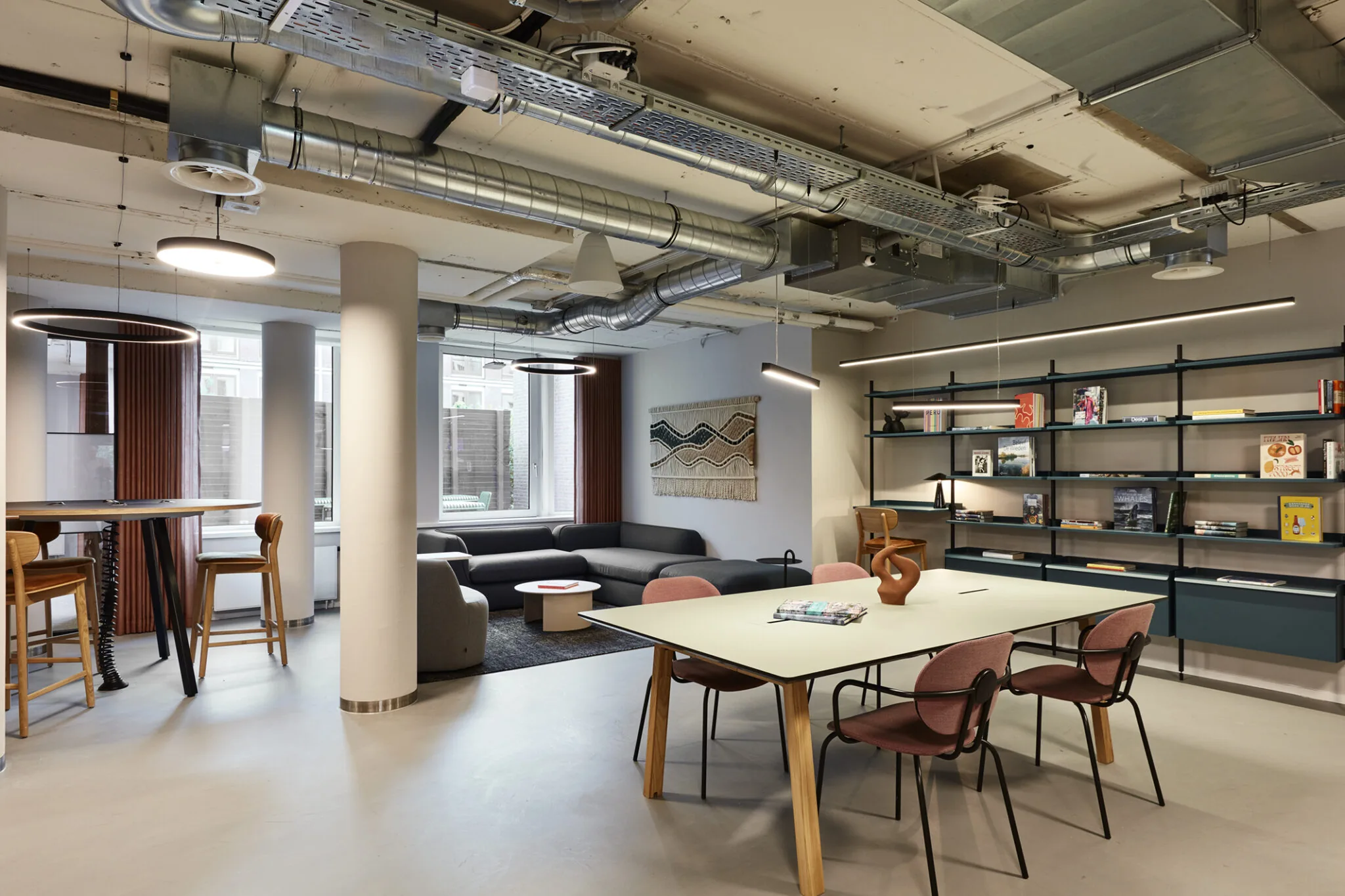 Moderne kantoorruimte aan de Koninginnegracht 10 in Den Haag met werktafels, een zithoek en open boekenkasten.