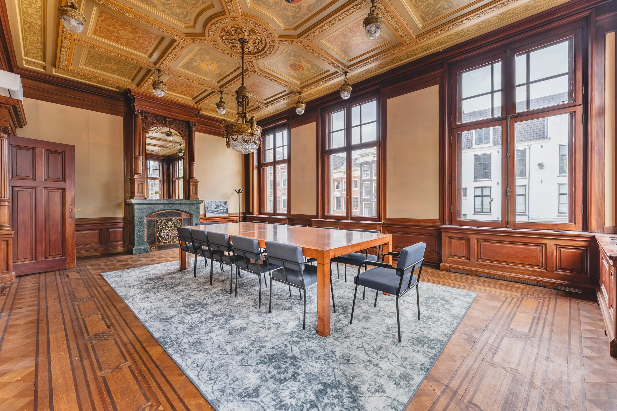 Een luxe vergaderruimte met een houten tafel, stoelen en een gedecoreerd plafond.
