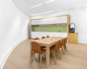 Moderne pantry met houten tafel en zes stoelen in kantoorruimte aan de Looskade 20 in Roermond.