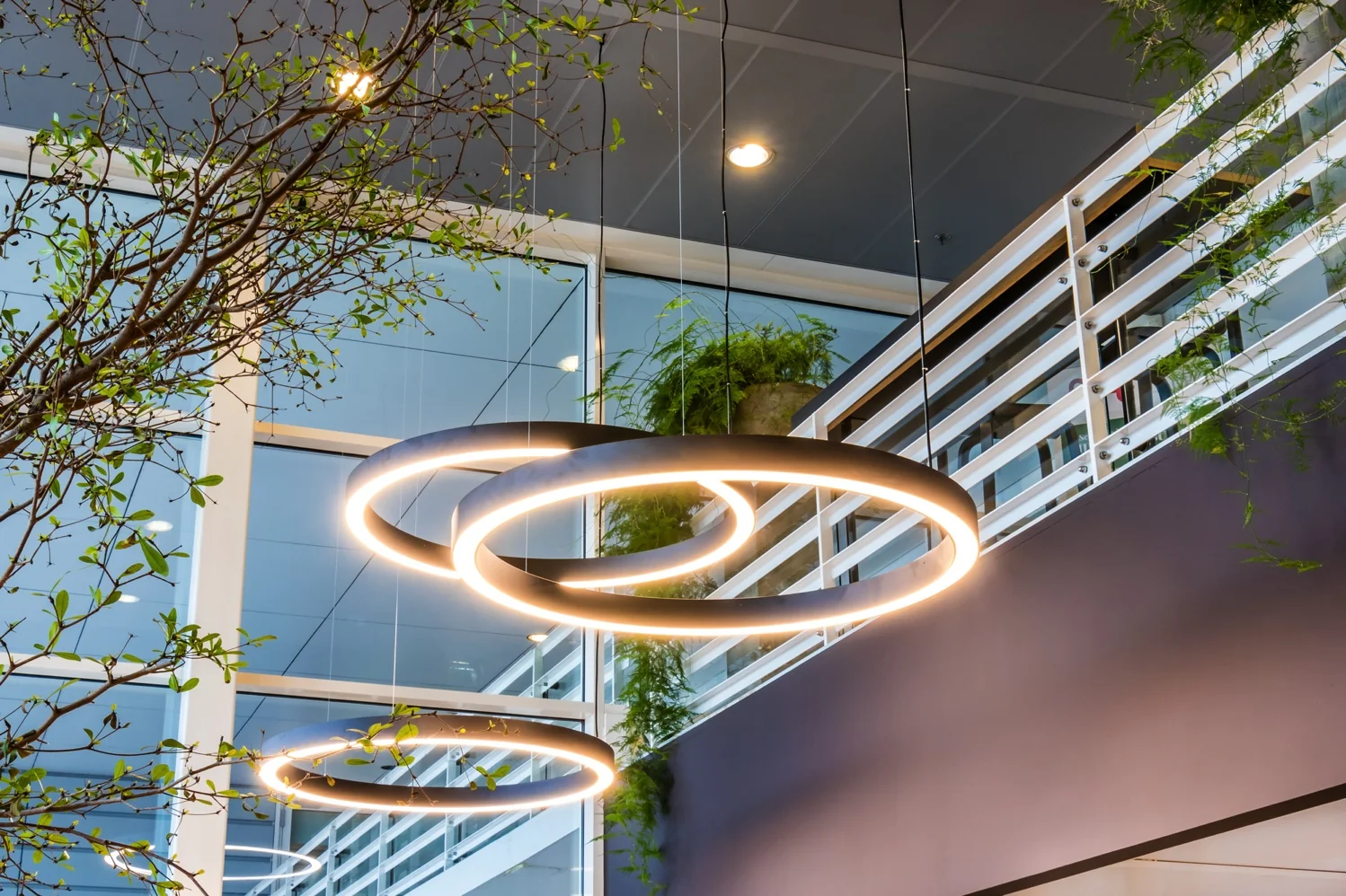 Moderne hanglampen in ringvorm verlichten een groen ingerichte kantoorruimte aan de Reactorweg.