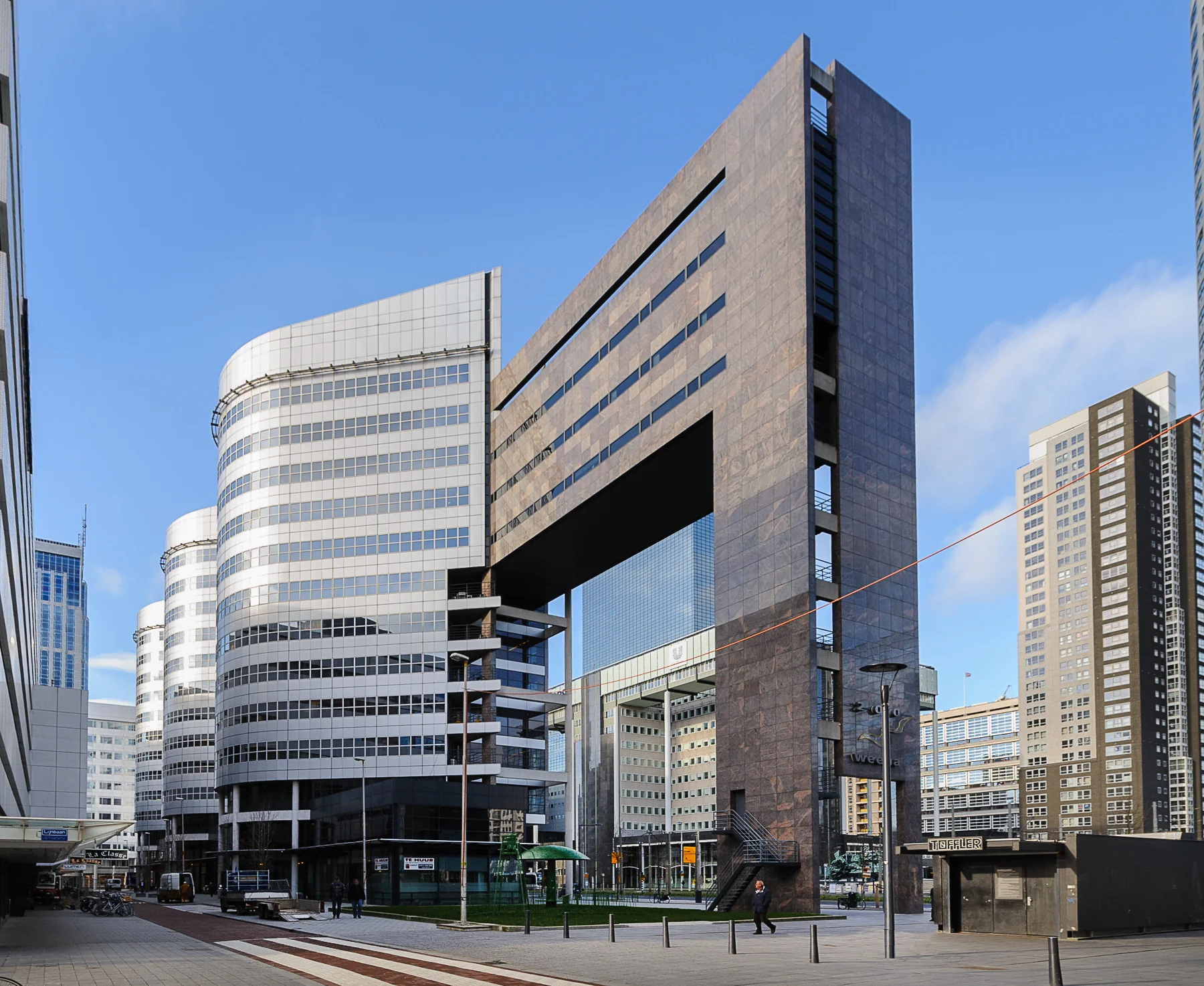 Modern kantoorgebouw aan de Weena in Rotterdam, omringd door wolkenkrabbers.