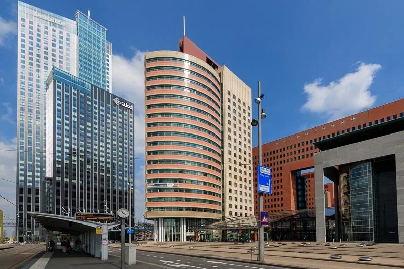 Moderne kantoorgebouwen en een tramhalte op het Wilhelminaplein in Rotterdam.