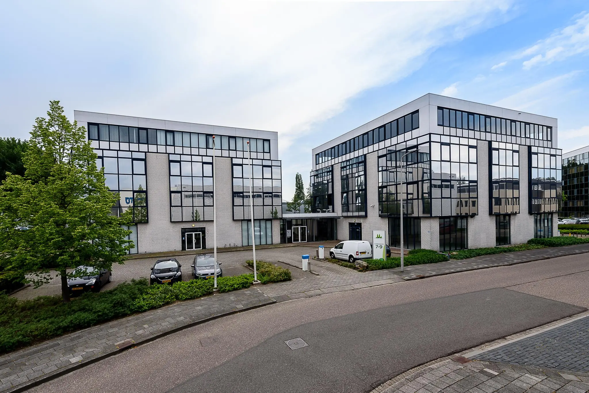 Twee moderne kantoorgebouwen aan de Cypresbaan met glazen gevels en geparkeerde auto's op de voorgrond.