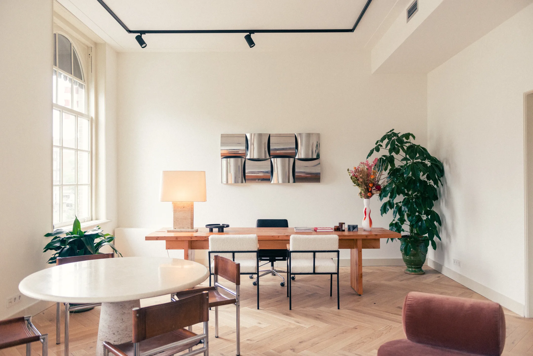 Een stijlvolle kantoorruimte met houten meubels, een grote plant en moderne kunst aan de muur.