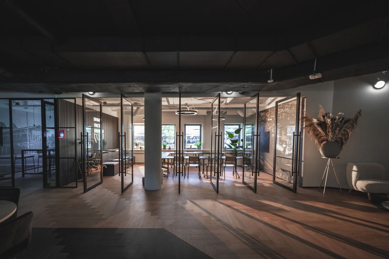 Modern kantoorinterieur met glazen vergaderruimtes, houten vloer en natuurlijk licht van drie ramen.