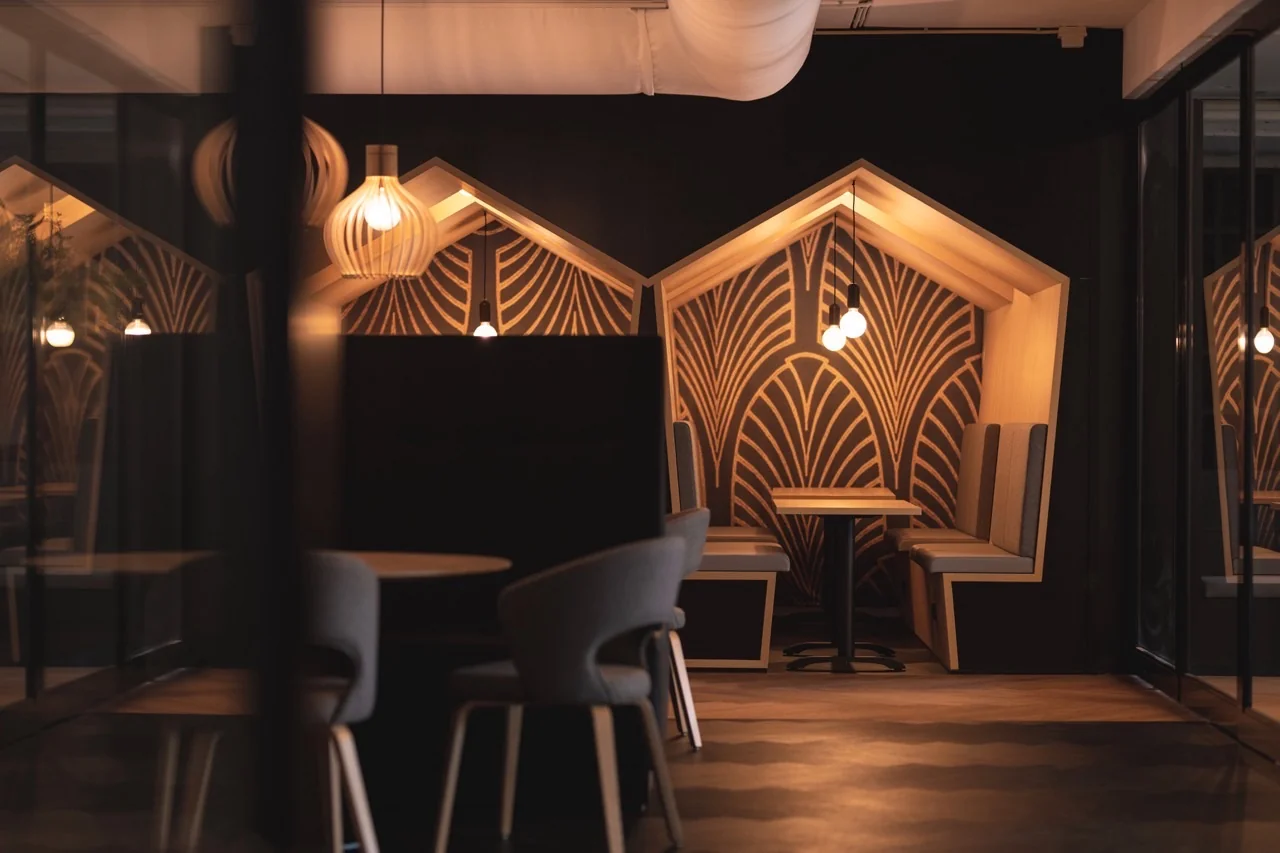 Sfeervol verlichte zithoeken in een modern interieur met houten nisjes en geometrisch patroon op de achterwand.