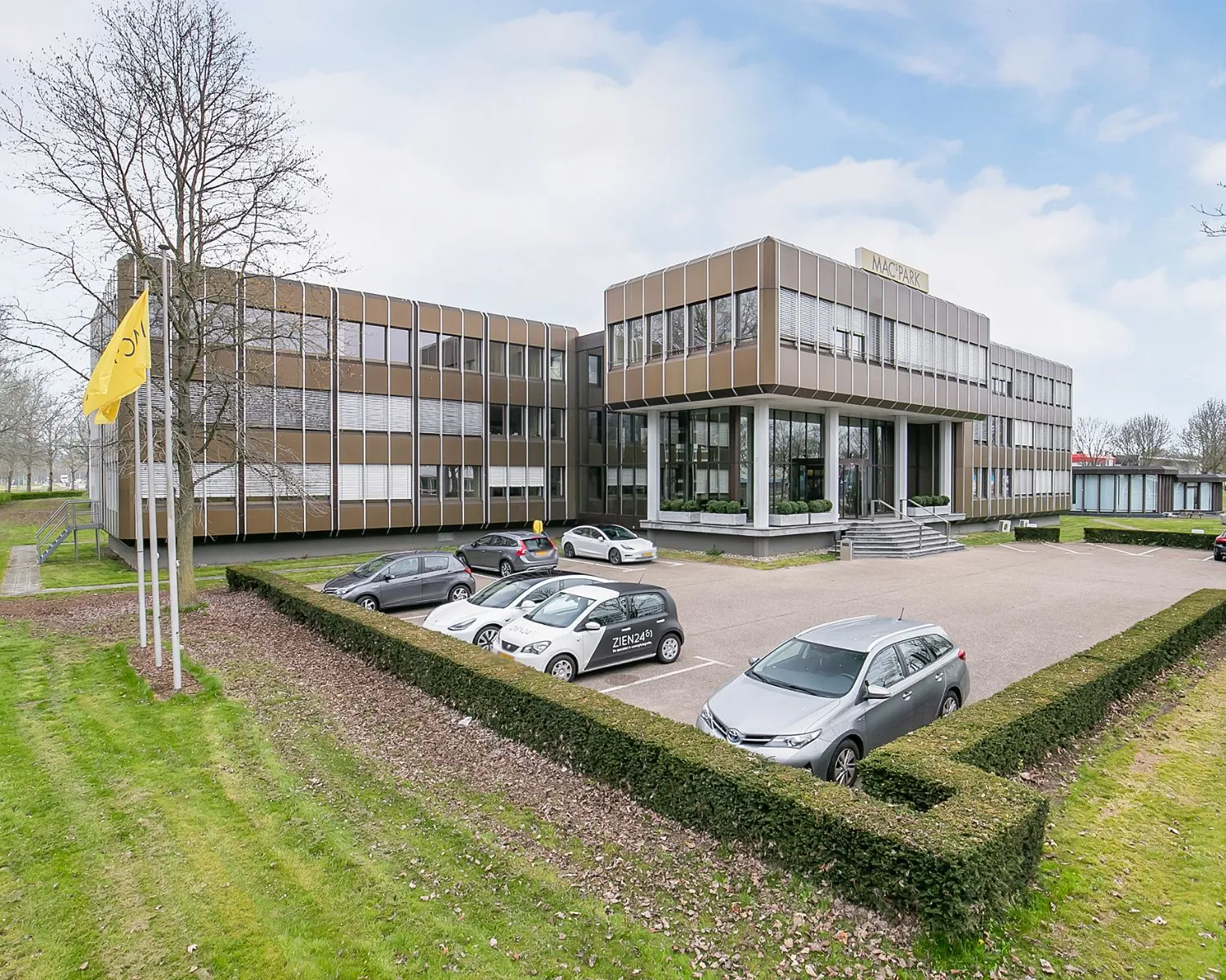 Modern kantoorpand aan de Bolderweg 1 in Almere met parkeerplaatsen en vlaggenmast op de voorgrond.