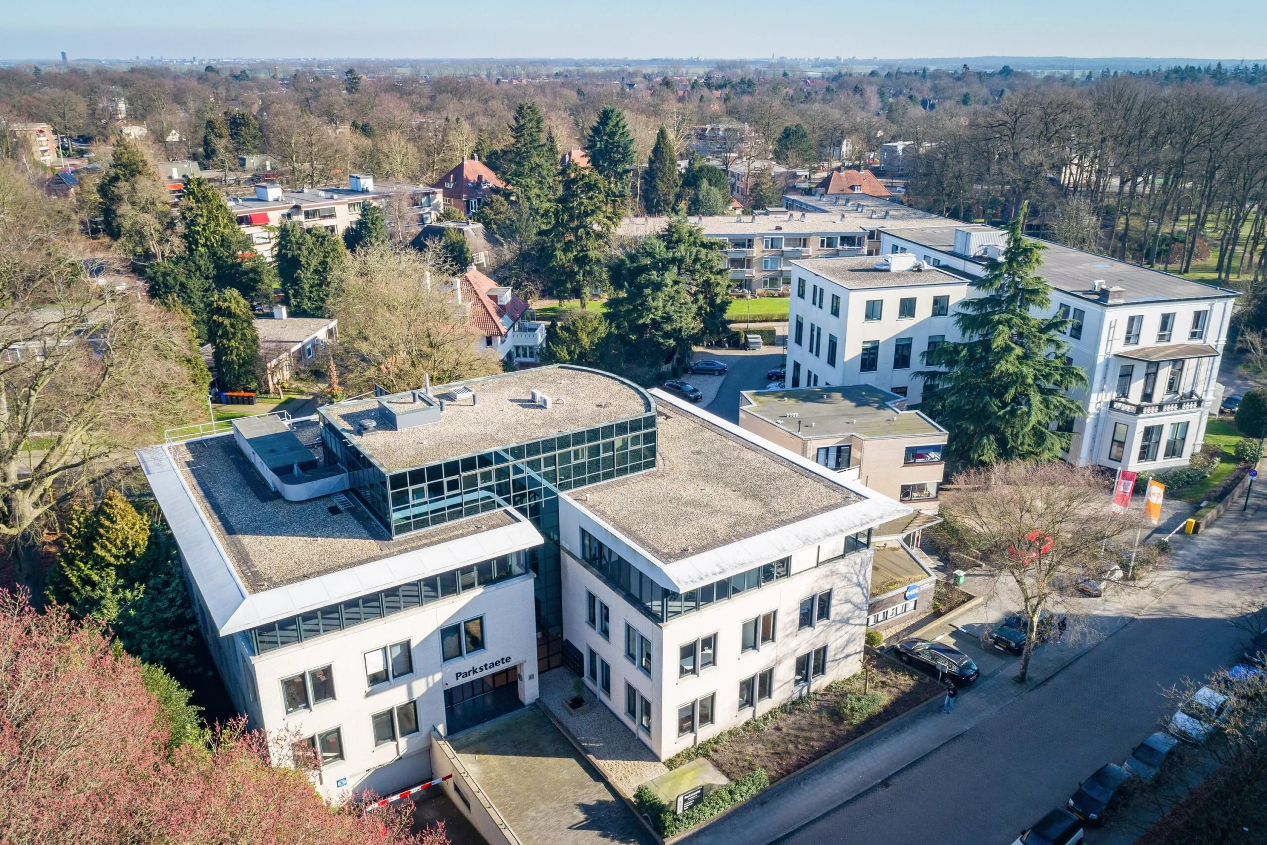 Luchtfoto van kantoorgebouw Parkstaete aan de Amalialaan, omringd door bomen en andere gebouwen.