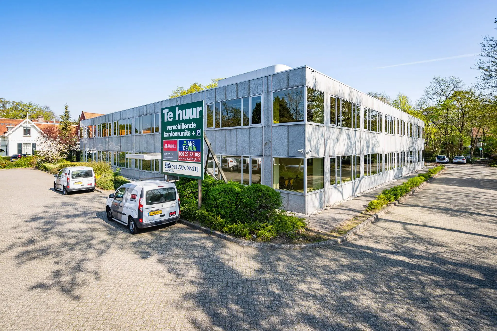 Twee verdiepingen tellend kantoorgebouw aan de Utrechtseweg met een bord "Te huur" voor verschillende kantoorunits en parkeerplaatsen.