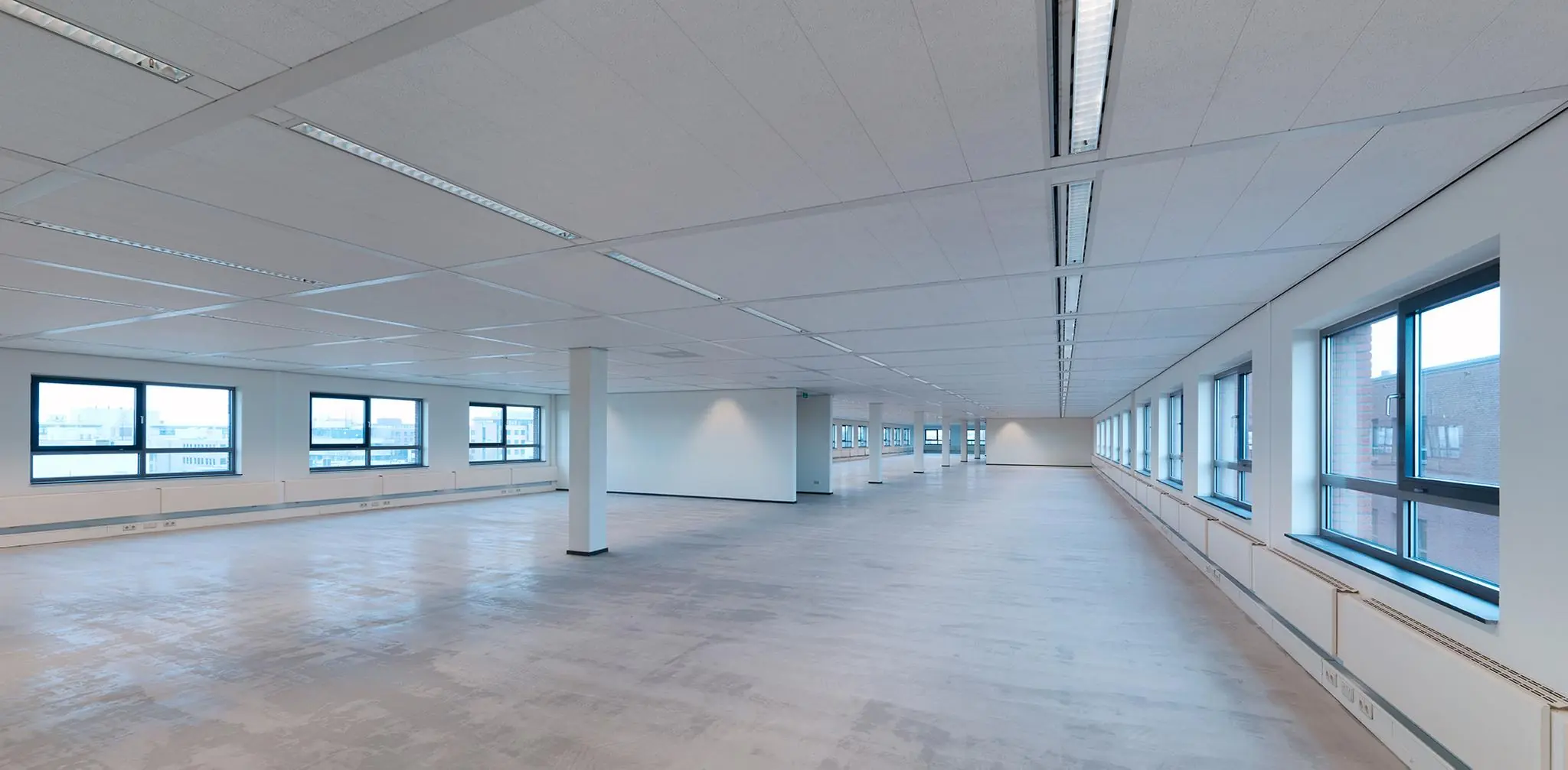 Lichte, lege kantoorruimte aan de Pompmolenlaan met grote ramen en systeemplafond.