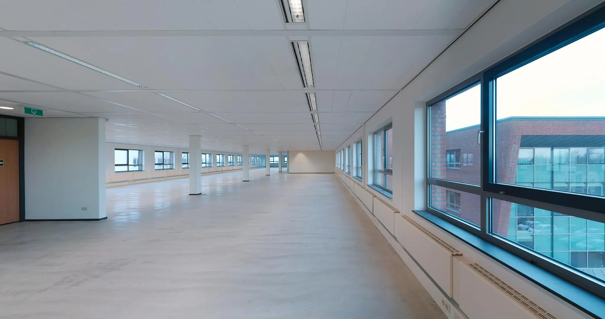 Leeg en licht kantoorpand aan de Pompmolenlaan met grote ramen en strakke witte afwerking.