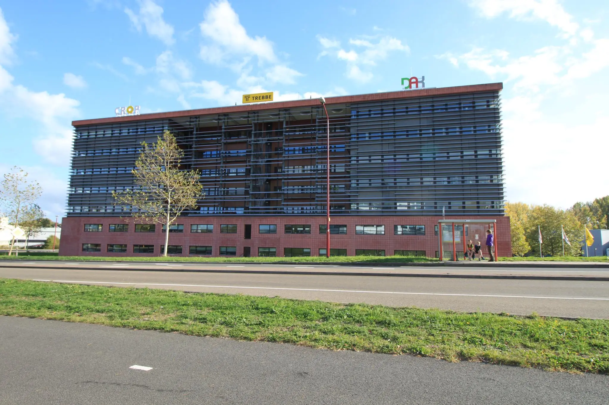 Kantoorgebouw aan de Marconibaan met bushalte en voorbijgangers op de voorgrond.