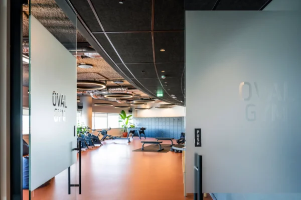 Een moderne gym genaamd "Oval Gym" met fitnessapparatuur en een stijlvolle inrichting.