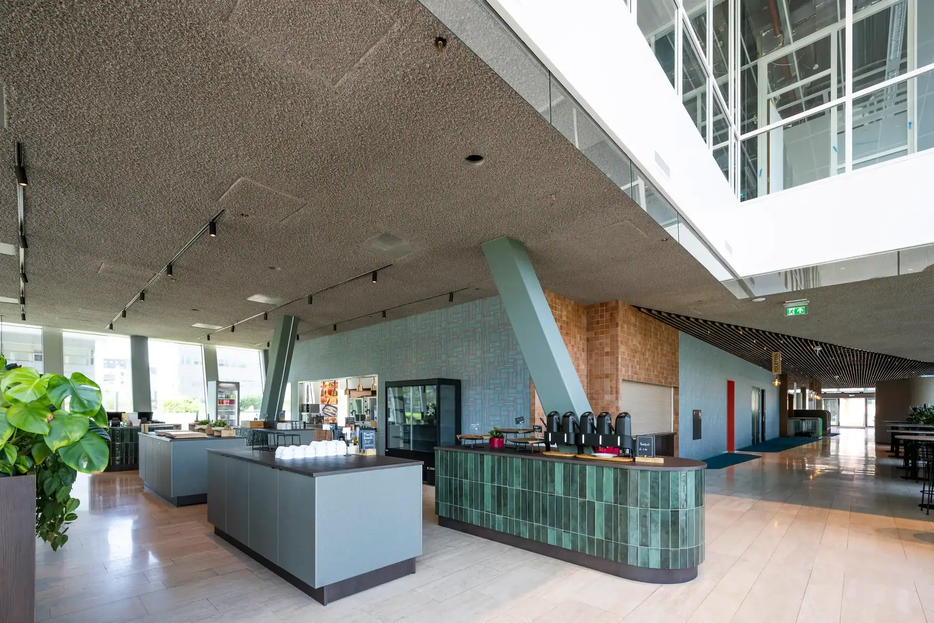 Modern restaurantinterieur met zelfbedieningsbalie, koffiehoek en ruime opstelling in een lichte, open ruimte.