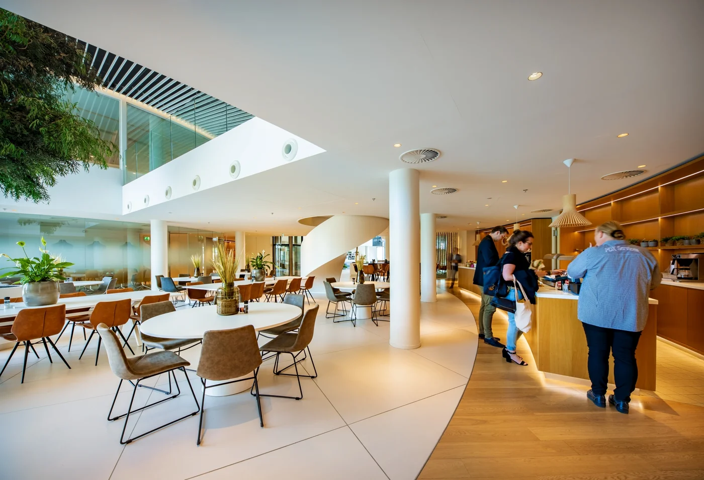 Een moderne kantoorruimte met een caféhoek en ronde tafels, gelegen aan de Euclideslaan.