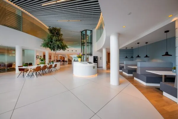 Een moderne kantoorlobby met zitplaatsen, een centrale ontvangstbalie en veel natuurlijke lichtinval.