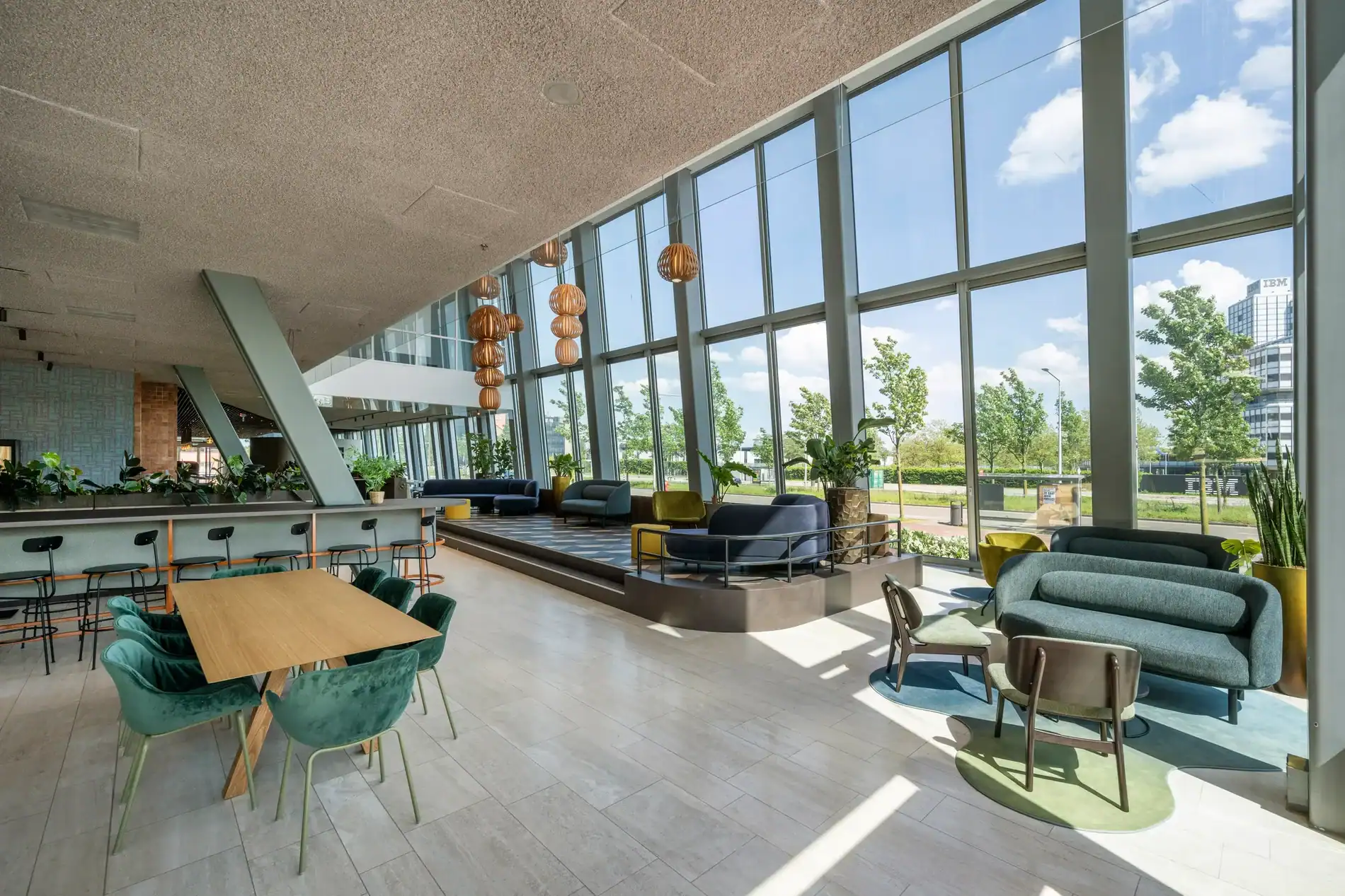 Lichte en moderne zithoek met eet- en loungeplekken in een ruimte met grote ramen en uitzicht op buiten.