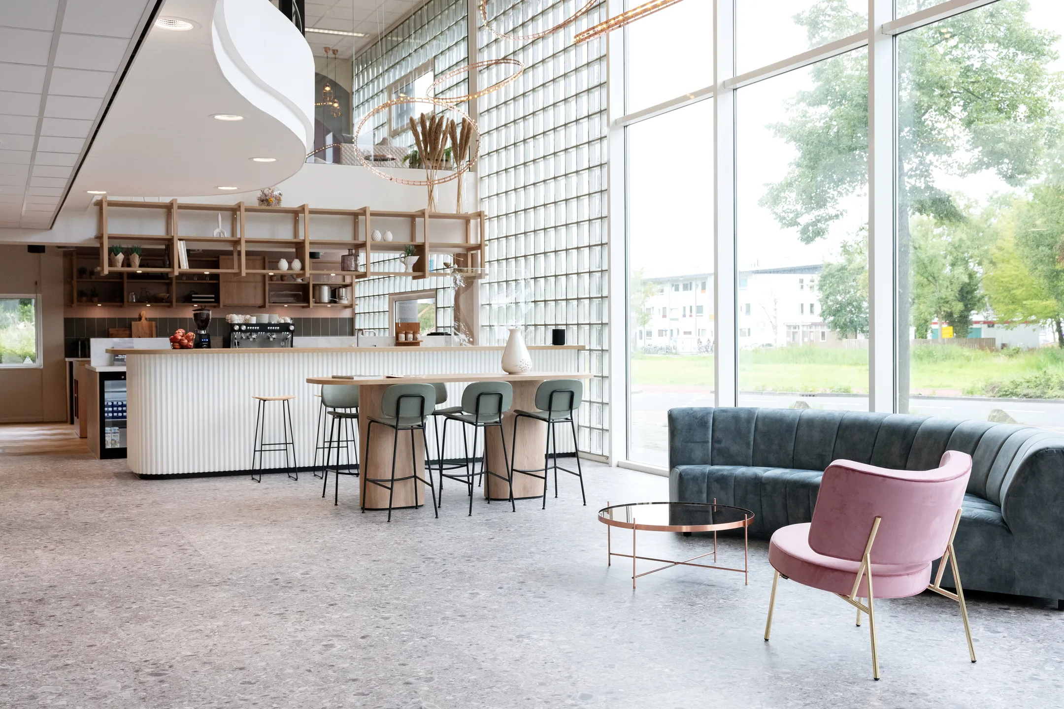 Een moderne, lichte ruimte met een stijlvolle bar, zitgedeelte en grote ramen met uitzicht op groen.