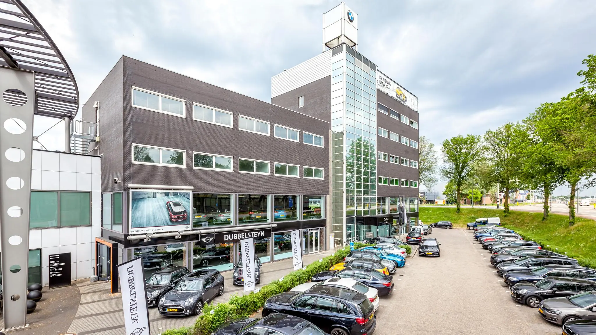 Voorgevel van het Dubbelsteyn autobedrijf aan de Mijlweg met geparkeerde auto’s op het terrein.