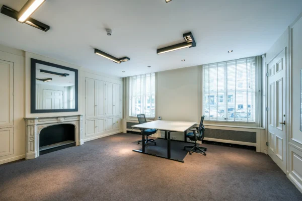 Een modern en licht kantoor met een open haard en twee bureaustoelen.